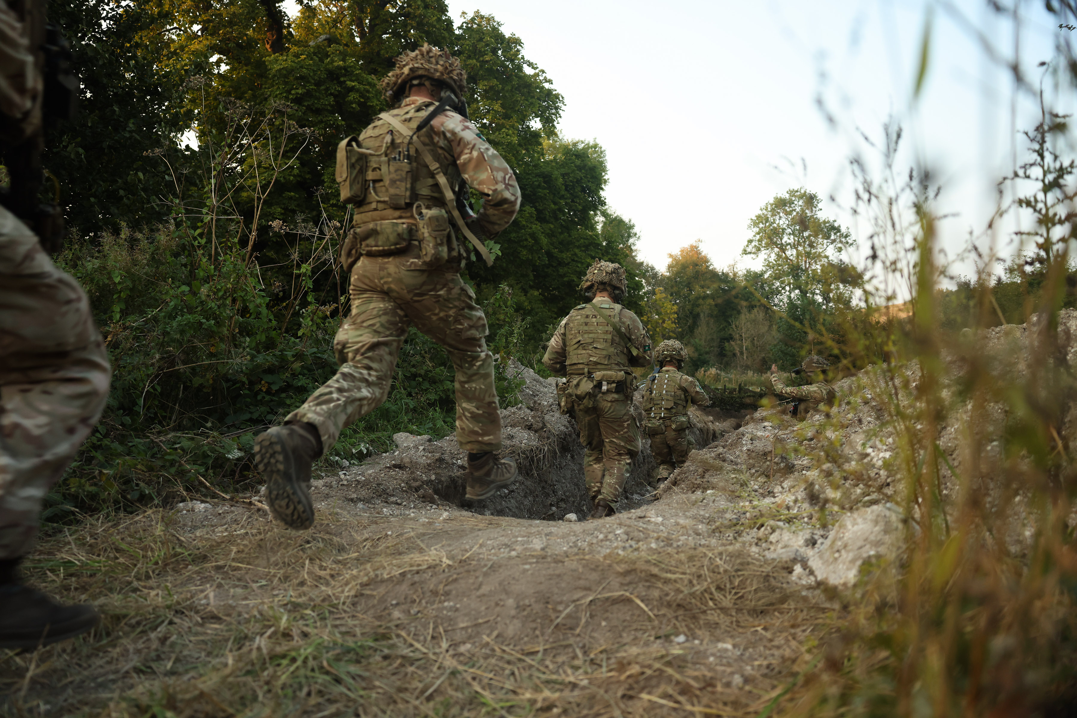 soldiers are pictured running into a trench whilst carrying weapons.