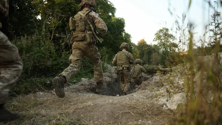 soldiers are pictured running into a trench whilst carrying weapons.