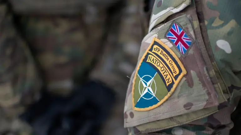 Camouflage uniform close up on the arm. NATO symbolic star shown with the colours green and blue. The Union Jack is placed above this.