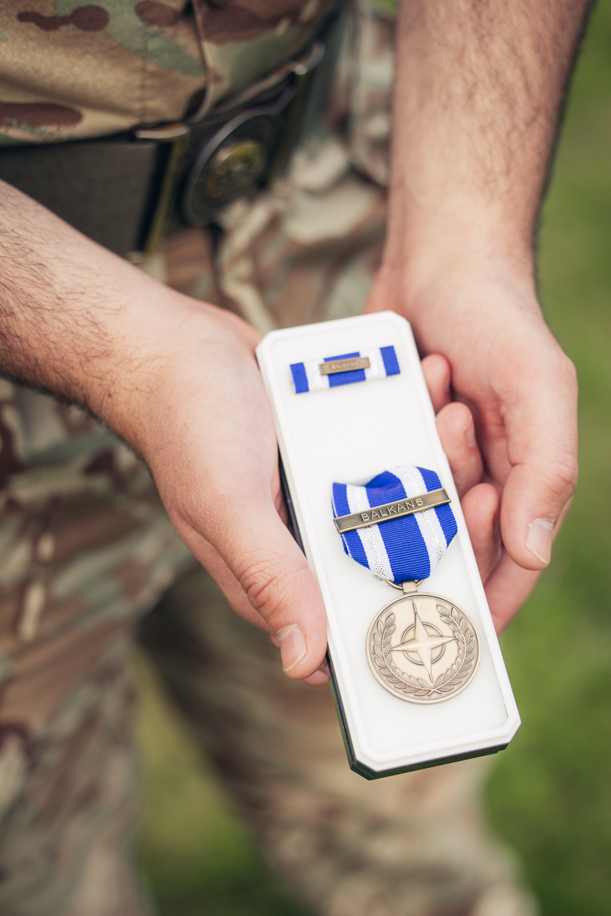 A close up of a medal, the ribbon is blue and white and says 'Balkans'.