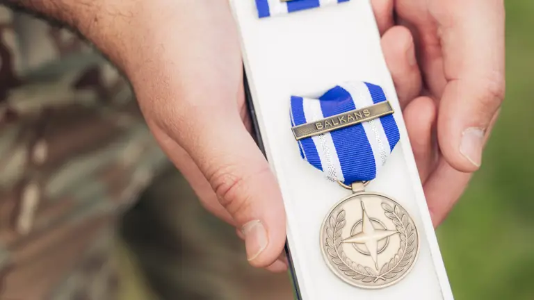 A close up of a medal, the ribbon is blue and white and says 'Balkans'.