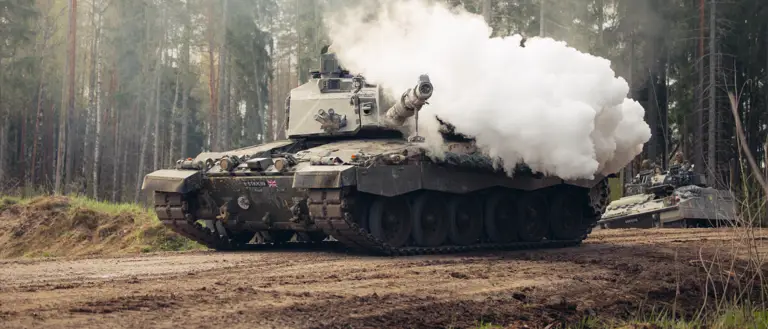 Smoke bellows from the gun of a tank.