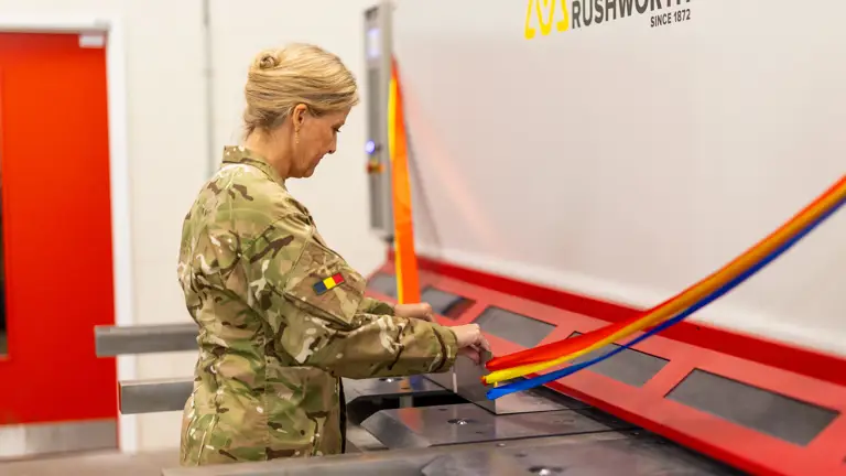 The Duchess of Edinburgh is seen wearing trousers and a camouflage print jacket stood testing out some equipment.