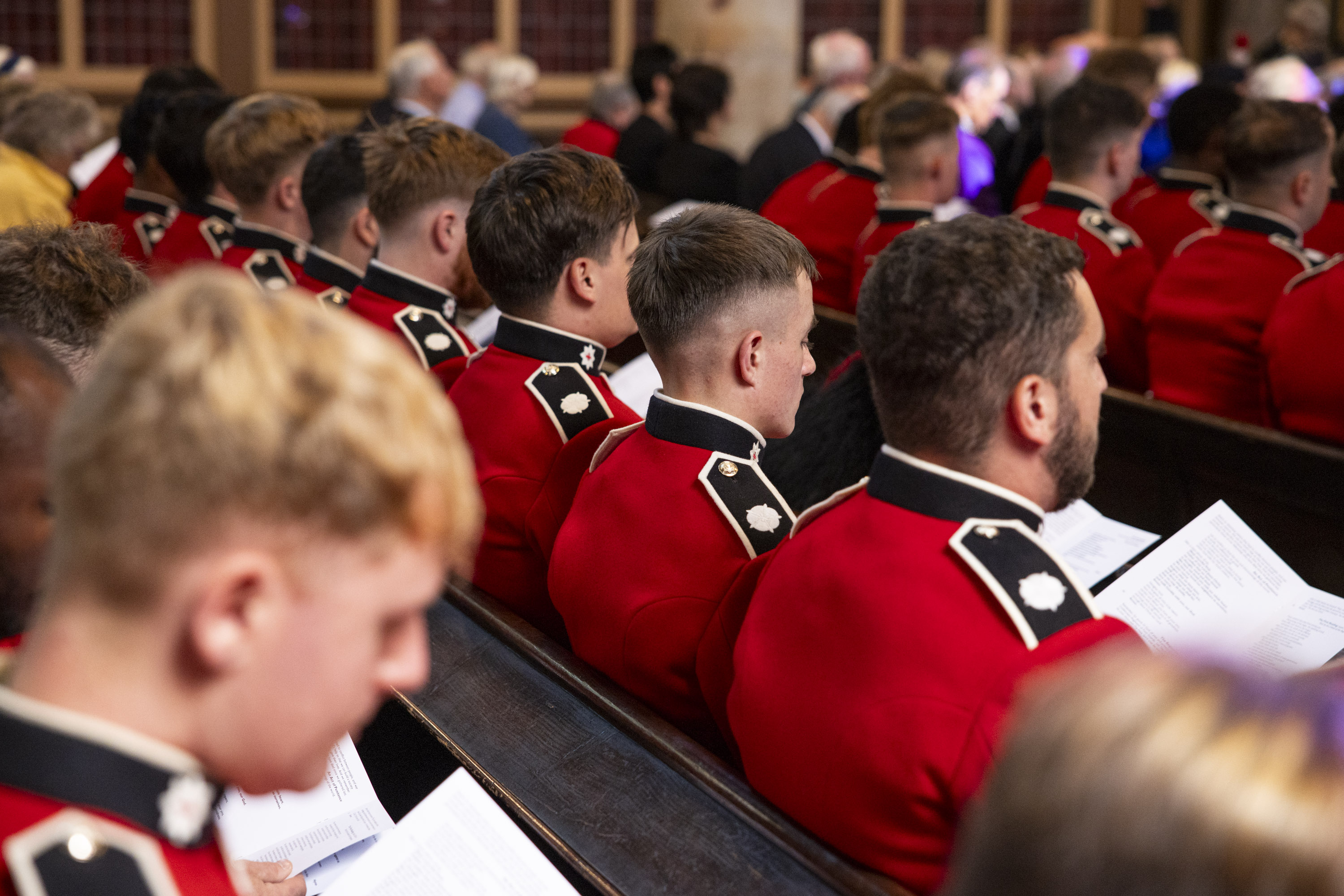 Soldiers wearing red tunics sit inside a church.