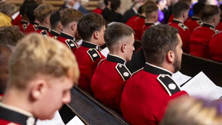 Soldiers wearing red tunics sit inside a church.