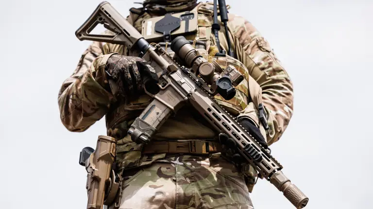 A close up of a soldier in uniform holding a rifle.