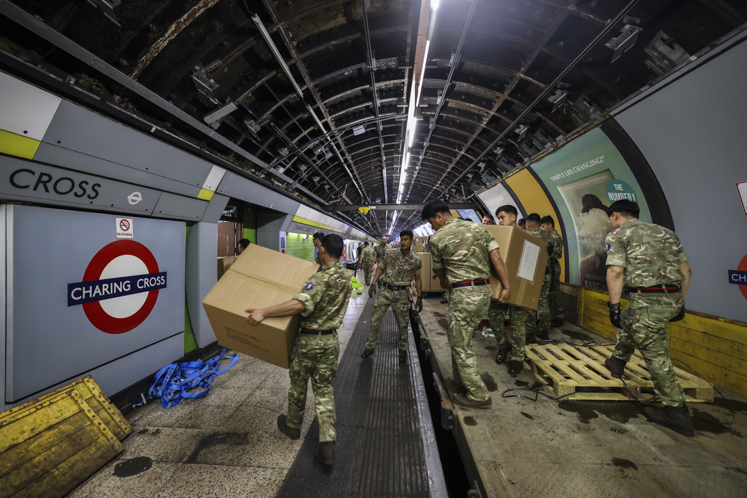 Military personnel in camouflage uniforms are moving large cardboard boxes in Charing Cross.