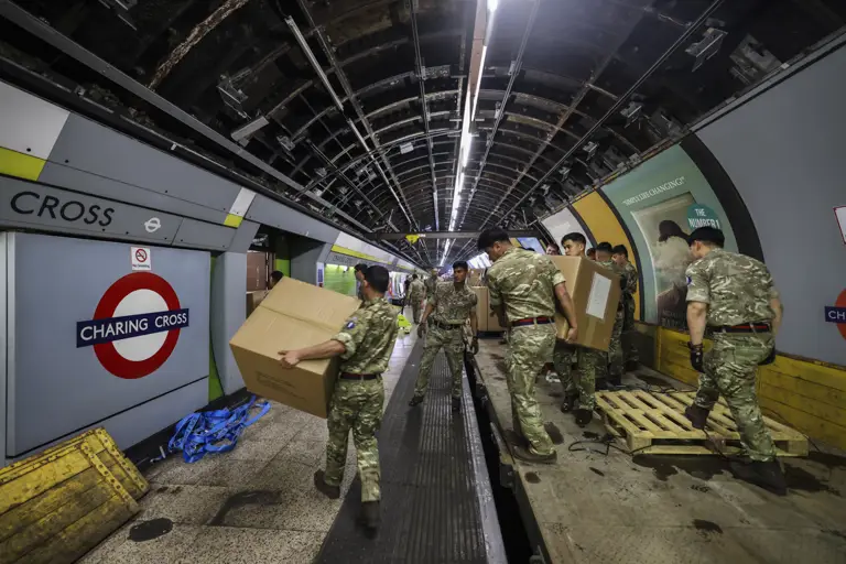Military personnel in camouflage uniforms are moving large cardboard boxes in Charing Cross.