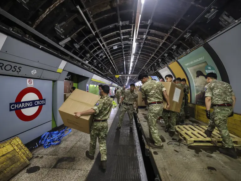 Military personnel in camouflage uniforms are moving large cardboard boxes in Charing Cross.