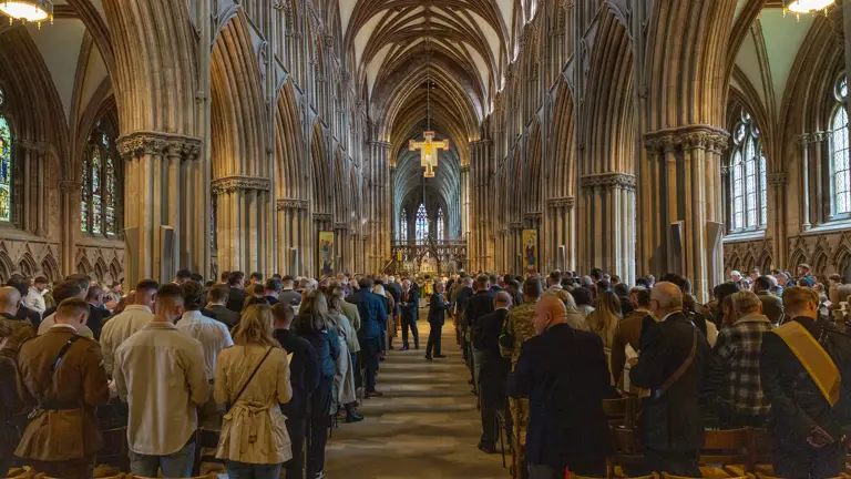 Inside the cathedral soldiers and guests line the chairs each side of the aisle. The colours are being marched down the aisle in uniform.