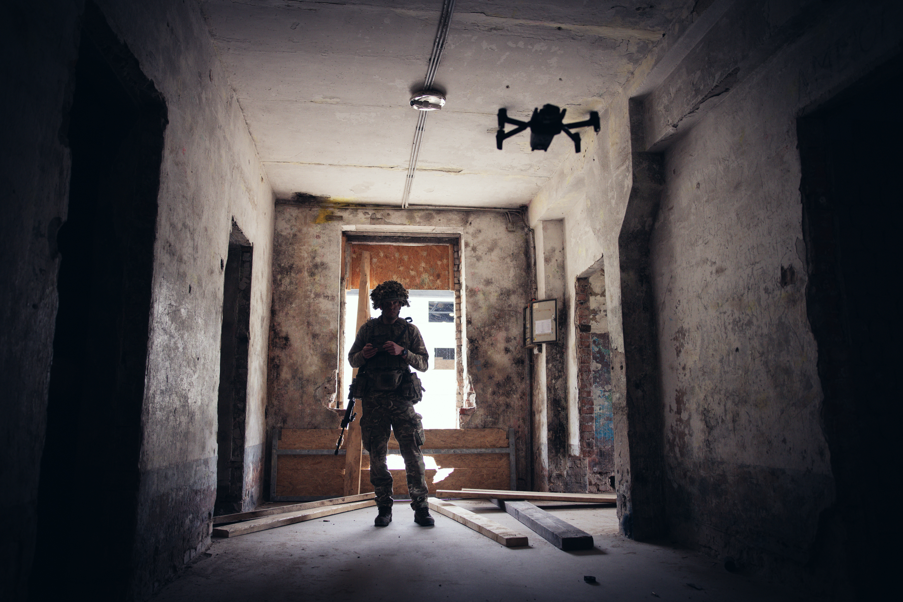 A soldier in uniform operates a drone inside of a building.
