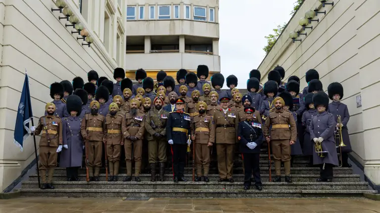 Group portrait of British soldiers and officers in ceremonial uniforms, including bearskin hats, standing on outdoor steps.