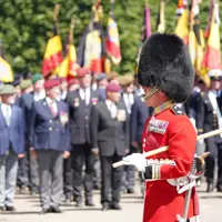 A person in a red ceremonial uniform and bearskin hat stands in the foreground.