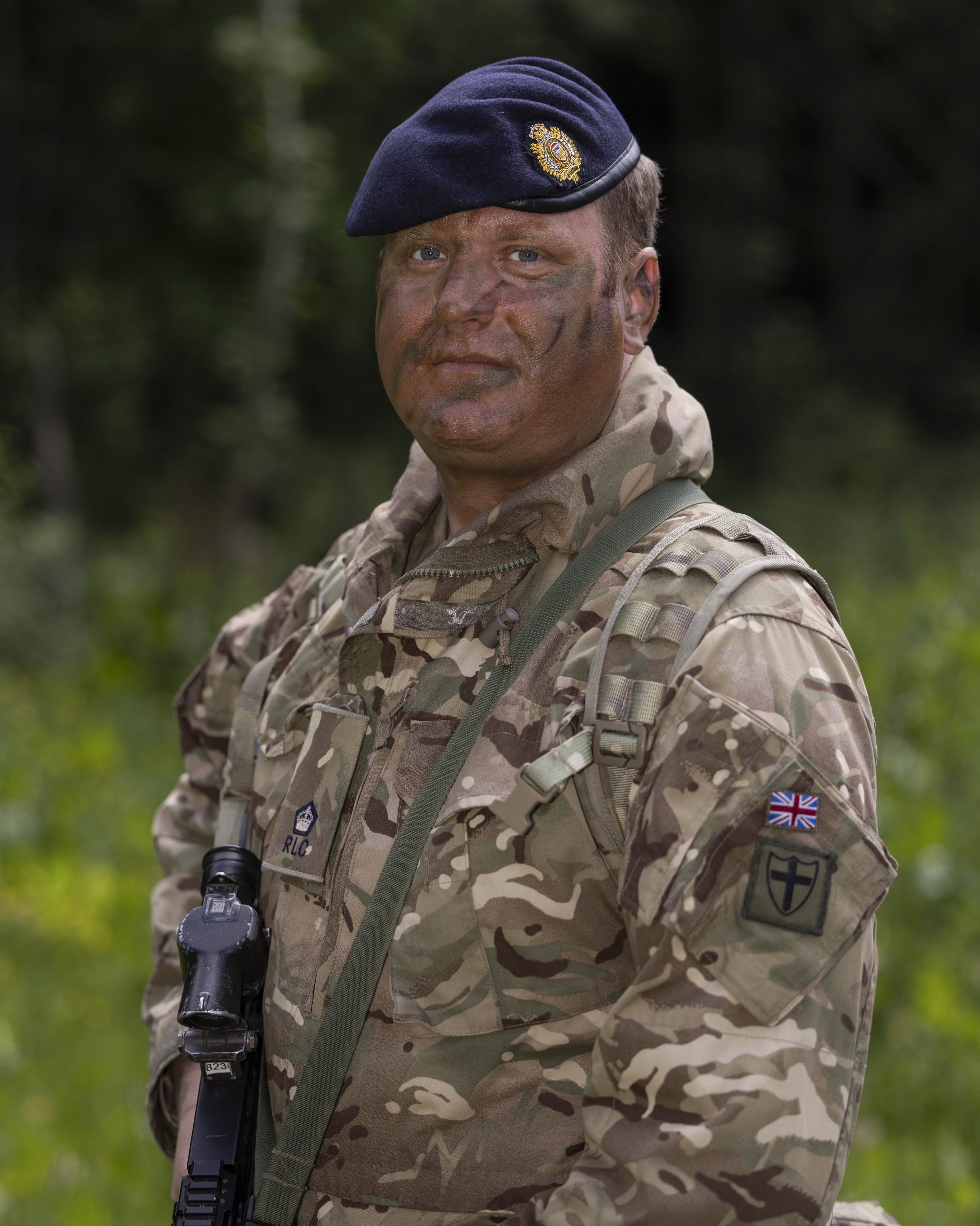 Portrait of soldier in camouflage uniform with dark blue hat holding a rifle  