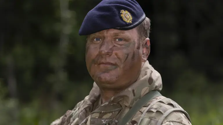 Portrait of soldier in camouflage uniform with dark blue hat holding a rifle