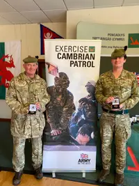 Two men in uniform are pictured with their Cambrian Patrol medals.