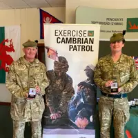 Two men in uniform are pictured with their Cambrian Patrol medals.