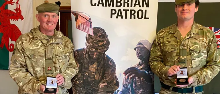 Two men in uniform are pictured with their Cambrian Patrol medals.