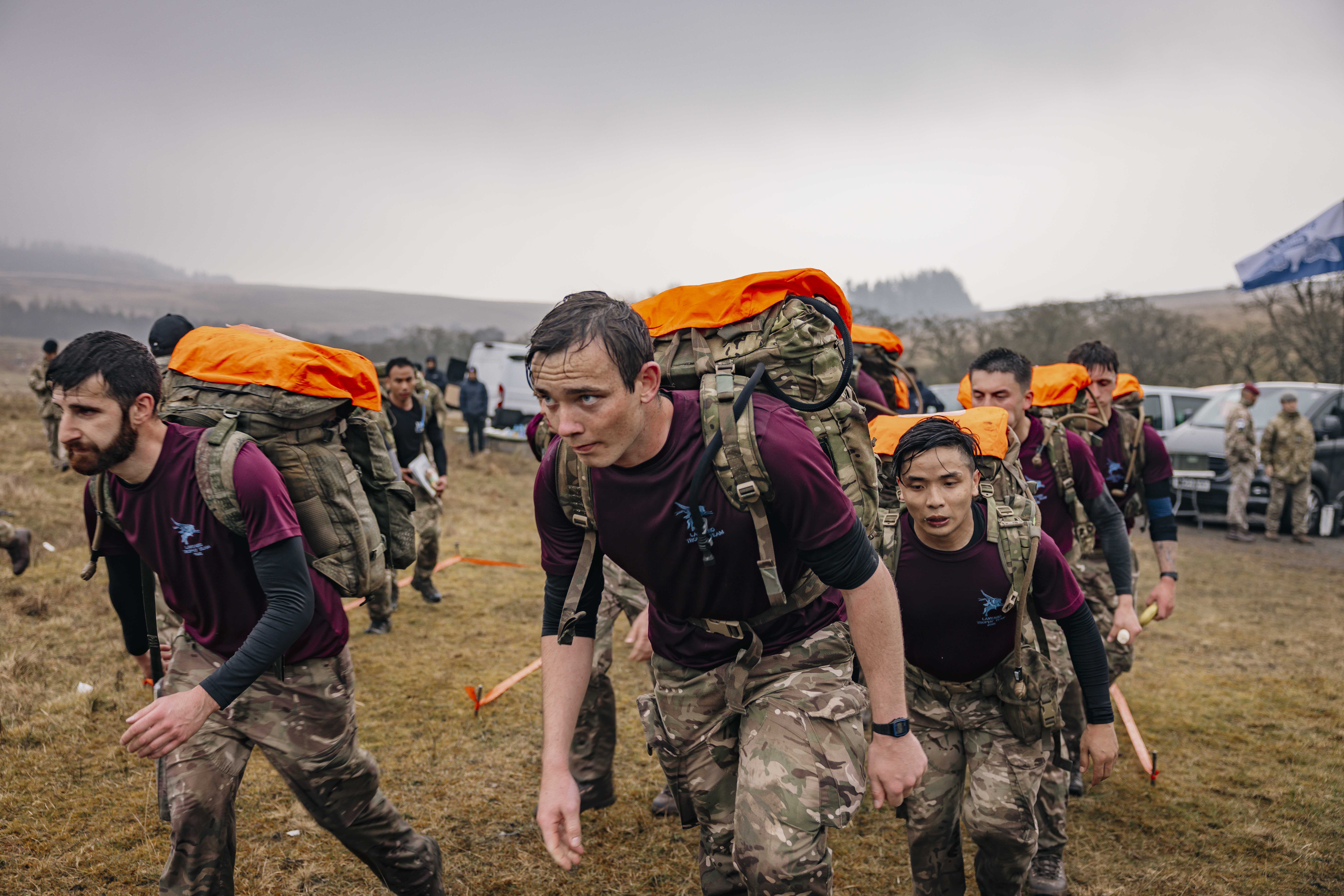 Soldiers from 216 (Para) Signals Squadron team set off to check point 4 during the 40 mile endurance march, wet from the rain and carrying a large green camouflage backpack with their gear.