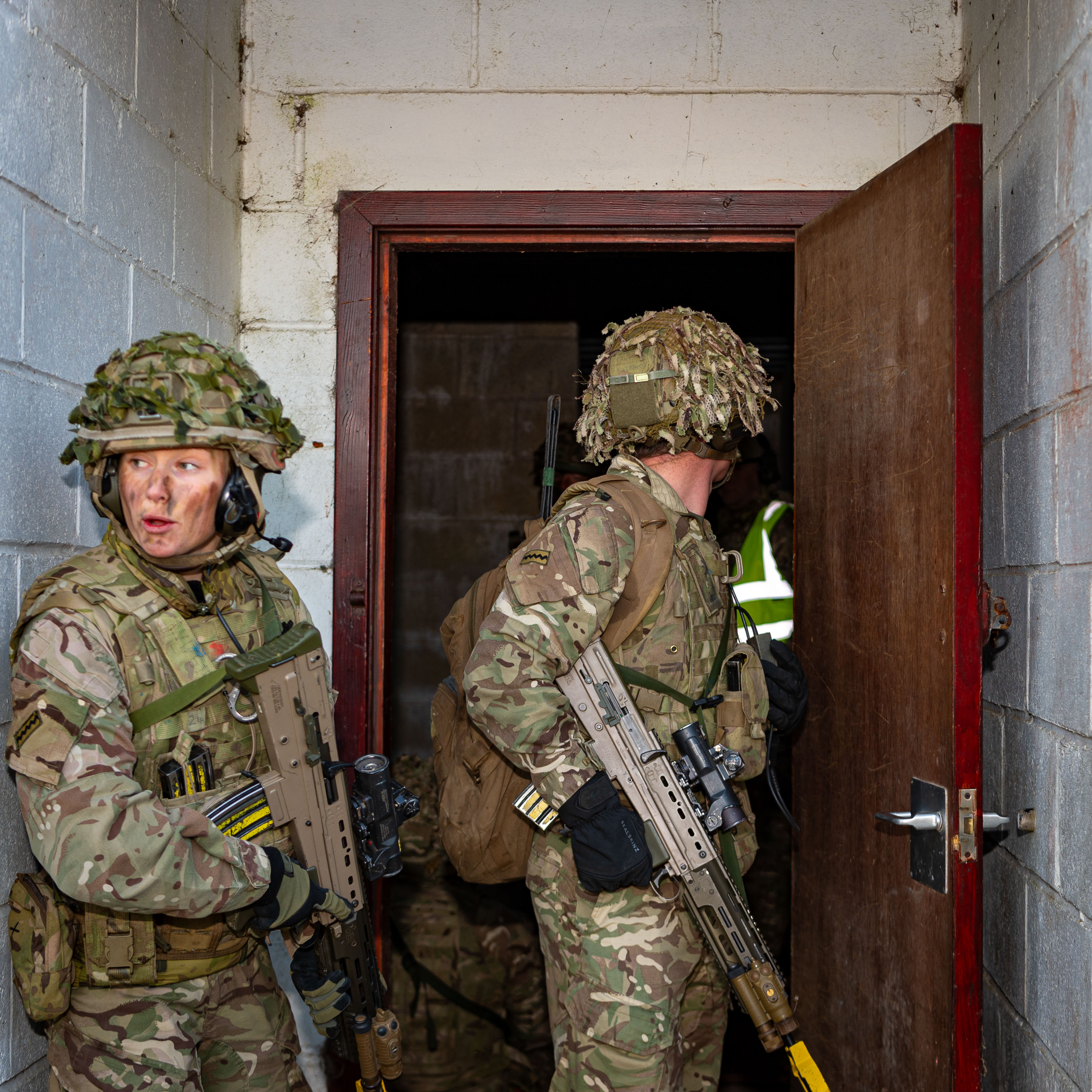 Two personnel in uniform are pictured within a doorway. 