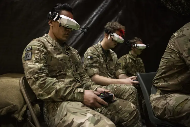 Three men in uniform are pictured with headset technology and controllers.