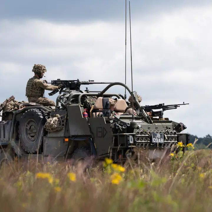 A Jackal vehicle is being manned with the weapon operated by a soldier. The vehicle sits in a field on exercise.