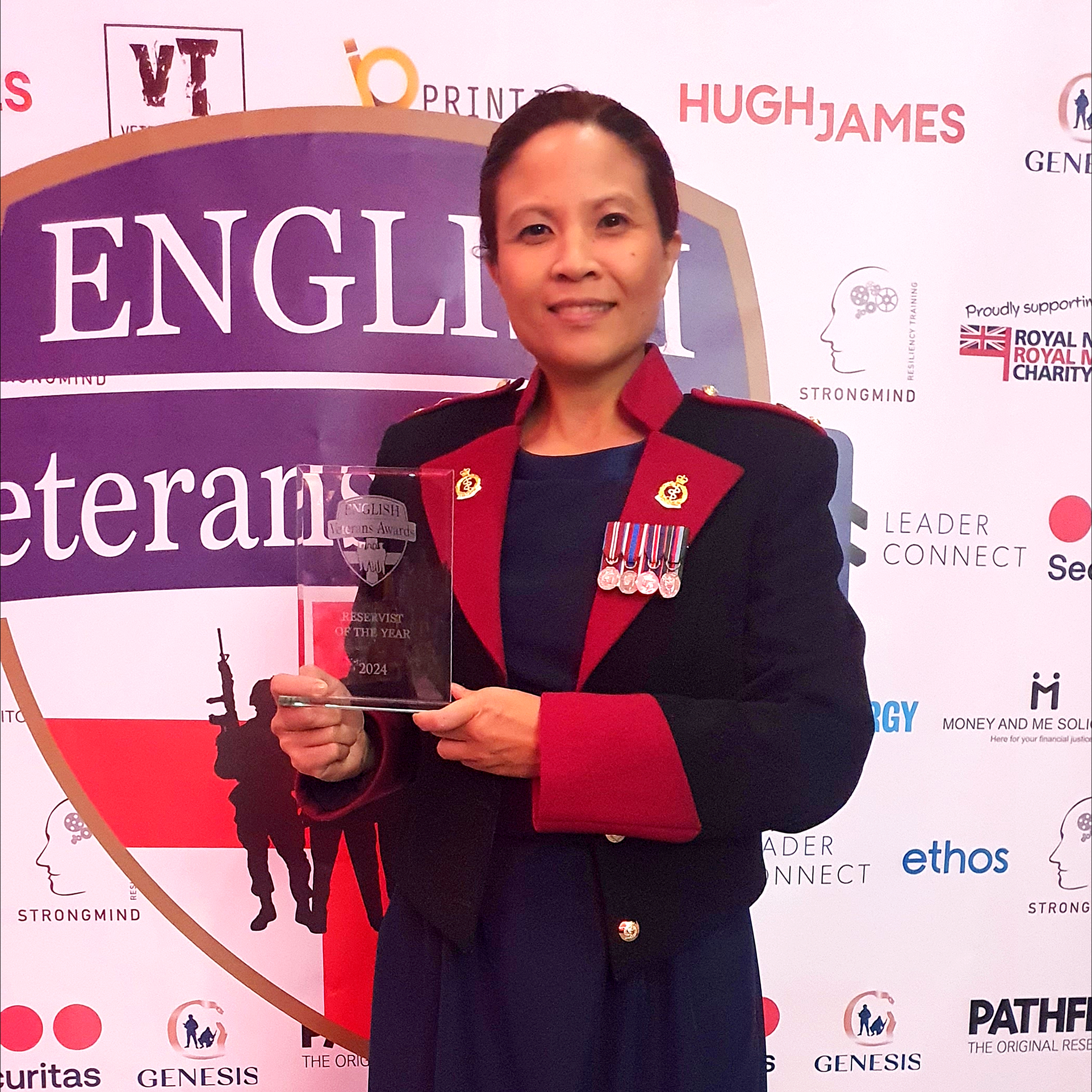 A lady in ceremonial attire holds an award. 