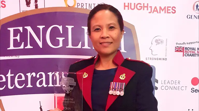 A lady in ceremonial attire holds an award.