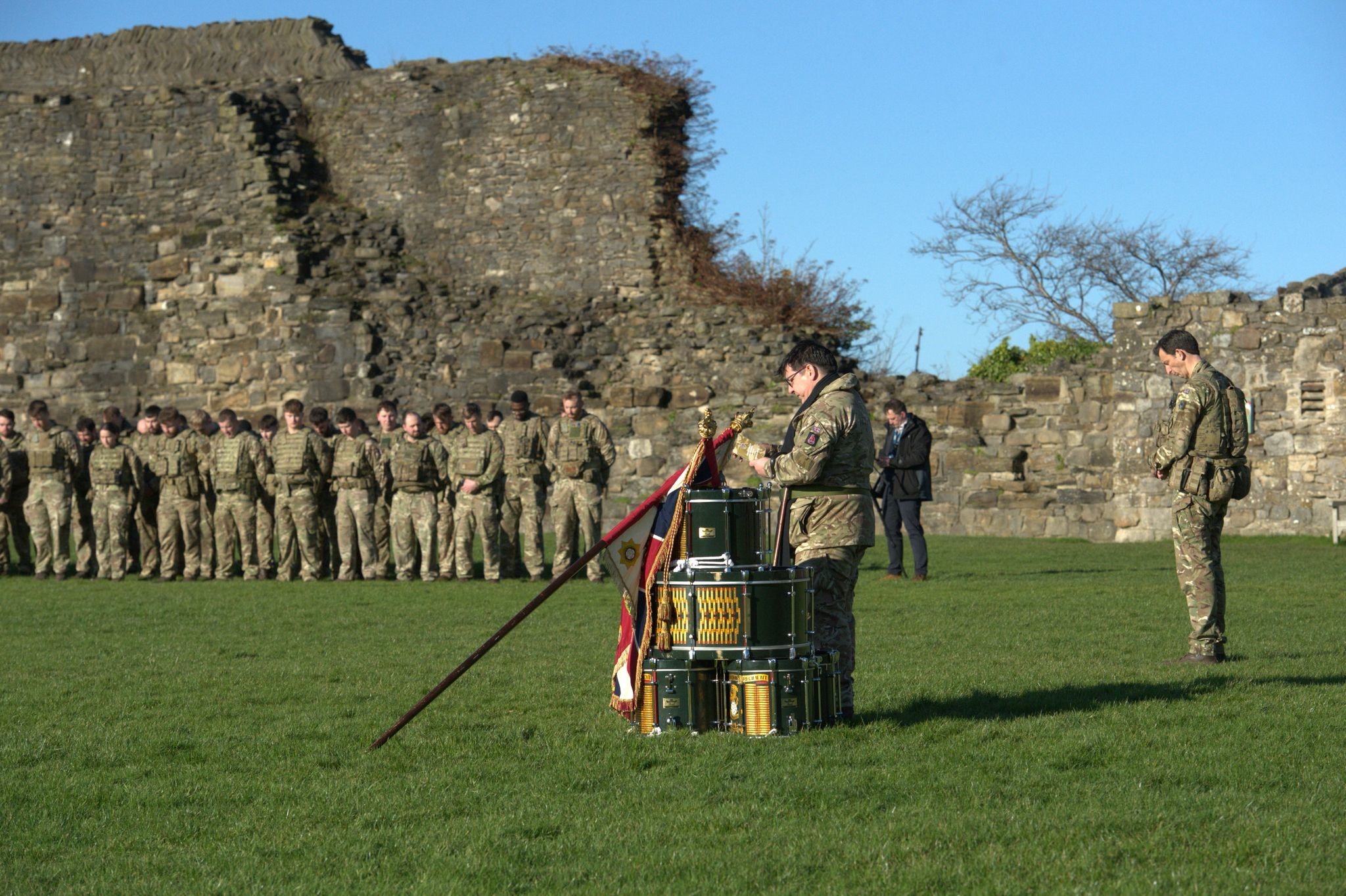 A number of soldiers are gathered around the perimeter of Richmond castle, a British Army Padre stands in the centre. 