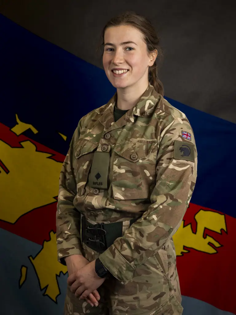 Female soldier stood posing for a portrait wearing her camouflage uniform.