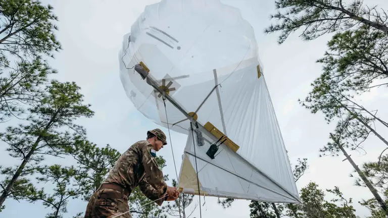 In a jungle environment, a British Army officer is prepared to raise a Helikite (balloon) attached with trail radio equipment to increase the range of the radio frequency.
