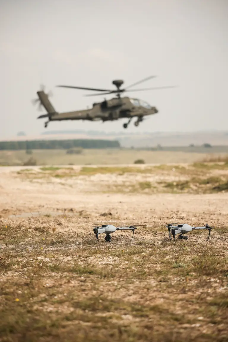 A helicopter is pictured in the background, drones are pictured closer to the camera.