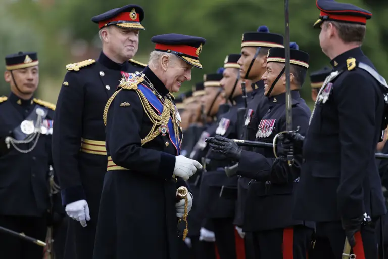 A group of uniformed individuals stands in formation outdoors. One individual, prominently positioned, is smiling.