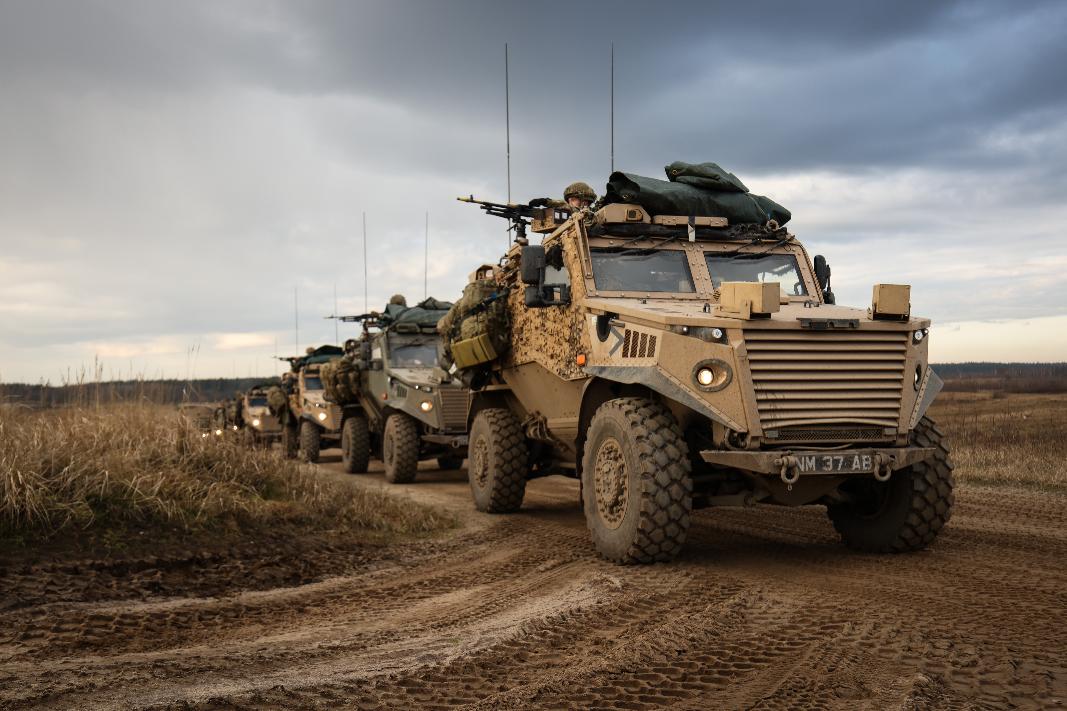 Multiple Foxhound vehicles photographed on exercise driving in convoy. The vehicles can be seen manned by soldiers. 