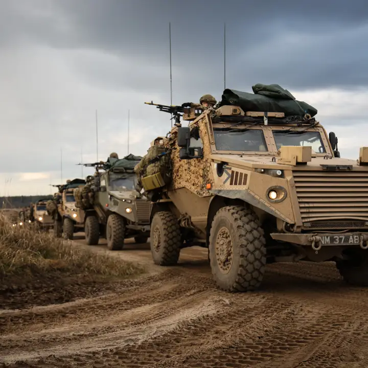 Multiple Foxhound vehicles photographed on exercise driving in convoy. The vehicles can be seen manned by soldiers.