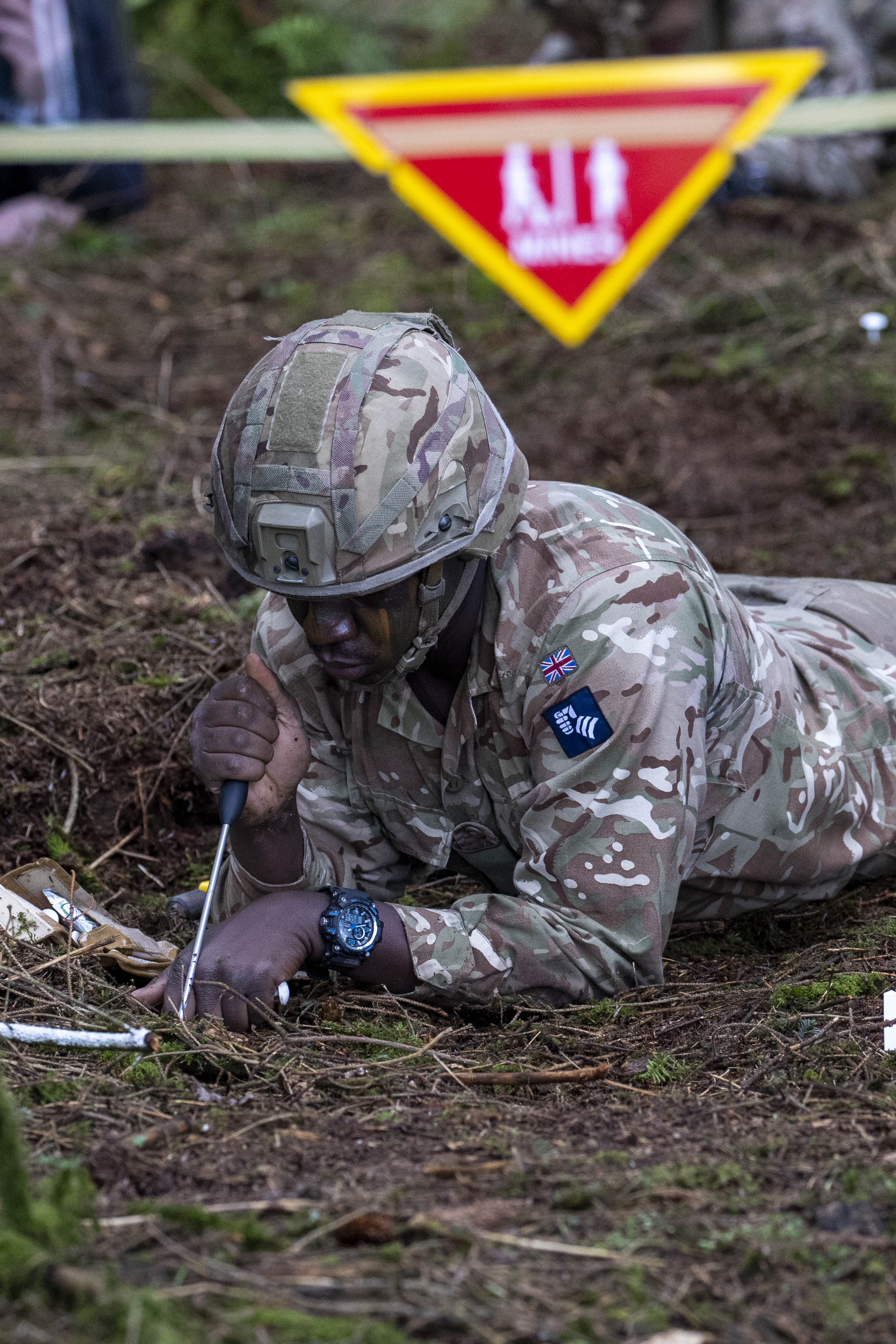 A man in uniform lays prone during a mine identification training exercise. 