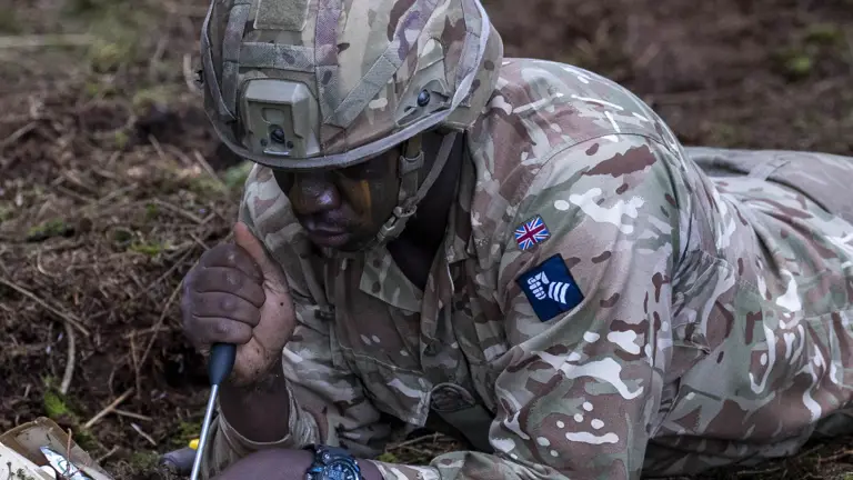 A man in uniform lays prone during a mine identification training exercise.