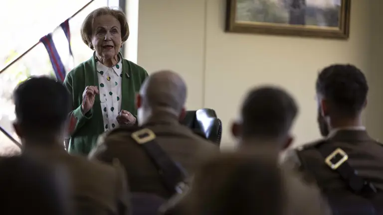 Mala Tribich MBE is stood in a room with a military audience to gives a survivor talk after the ceremony.