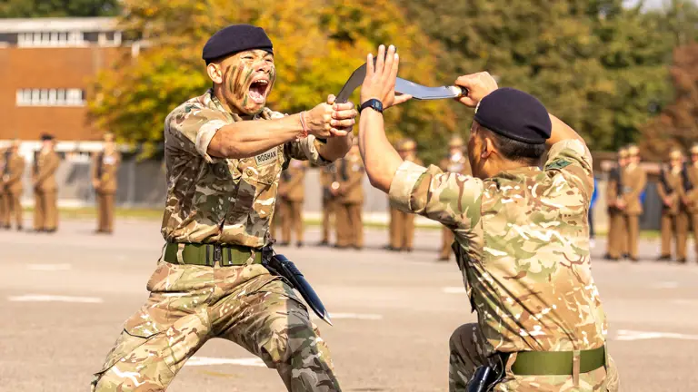 Two soldiers in uniform perform a dance with a Nepali ceremonial knife.
