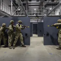 Soldiers in camouflage uniforms holding rifles stand ready in concrete building