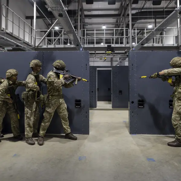 Soldiers in camouflage uniforms holding rifles stand ready in concrete building
