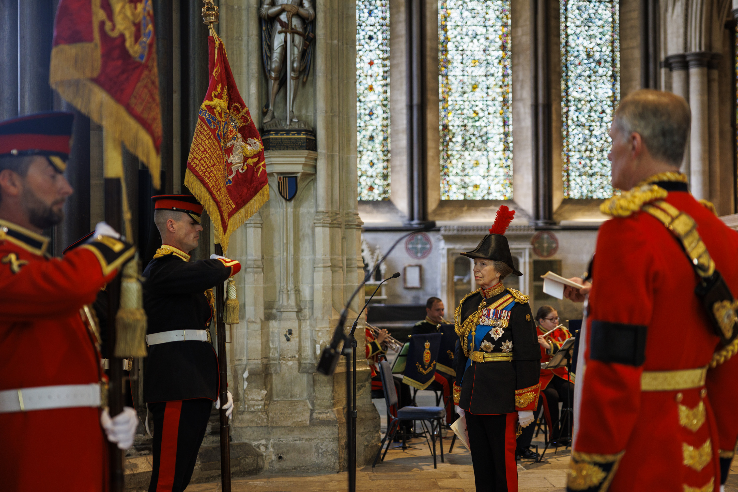 Two people dressed in military ceremonial uniform. They are holding ceremonial flags.