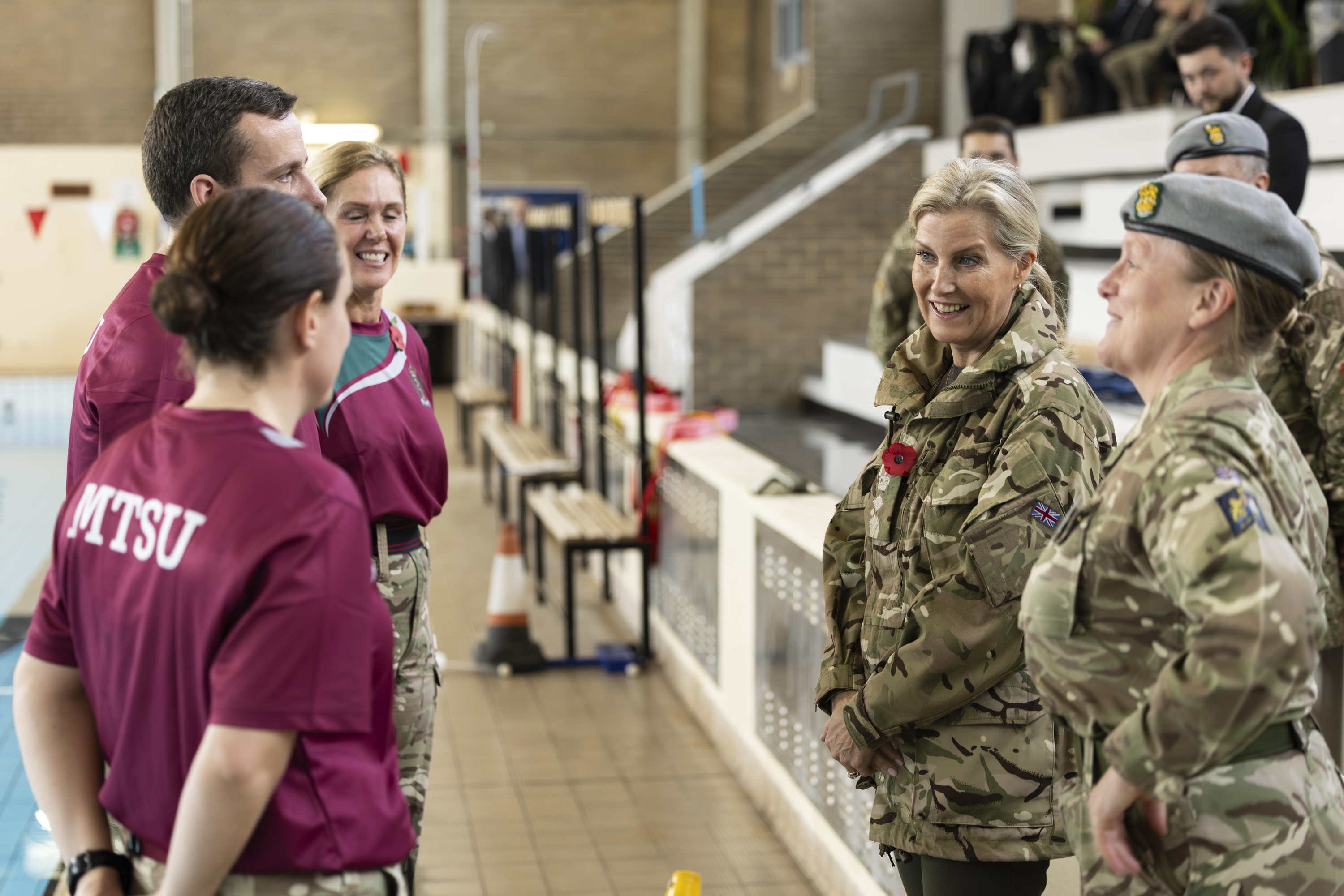 Two groups, one in maroon MTSU shirts and the other in camouflage military uniforms, stand facing each other.