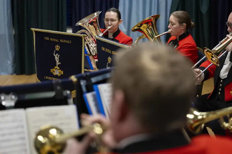 A brass band in red and black uniforms plays with focus and precision.