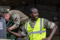 Two soldiers in uniform are pictured working with machinery