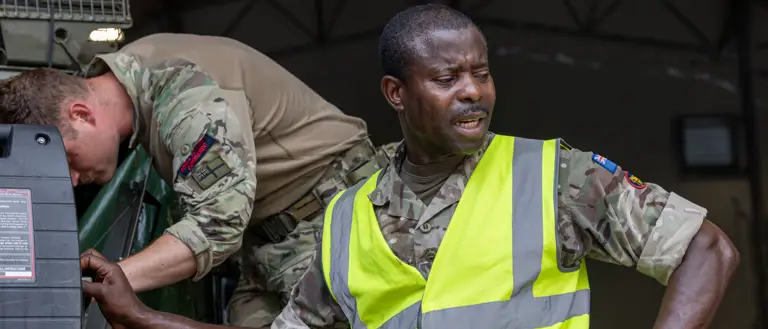 Two soldiers in uniform are pictured working with machinery