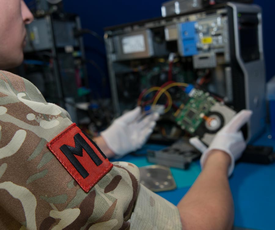 Military Police digital forensic specialist examining a computer hard drive.