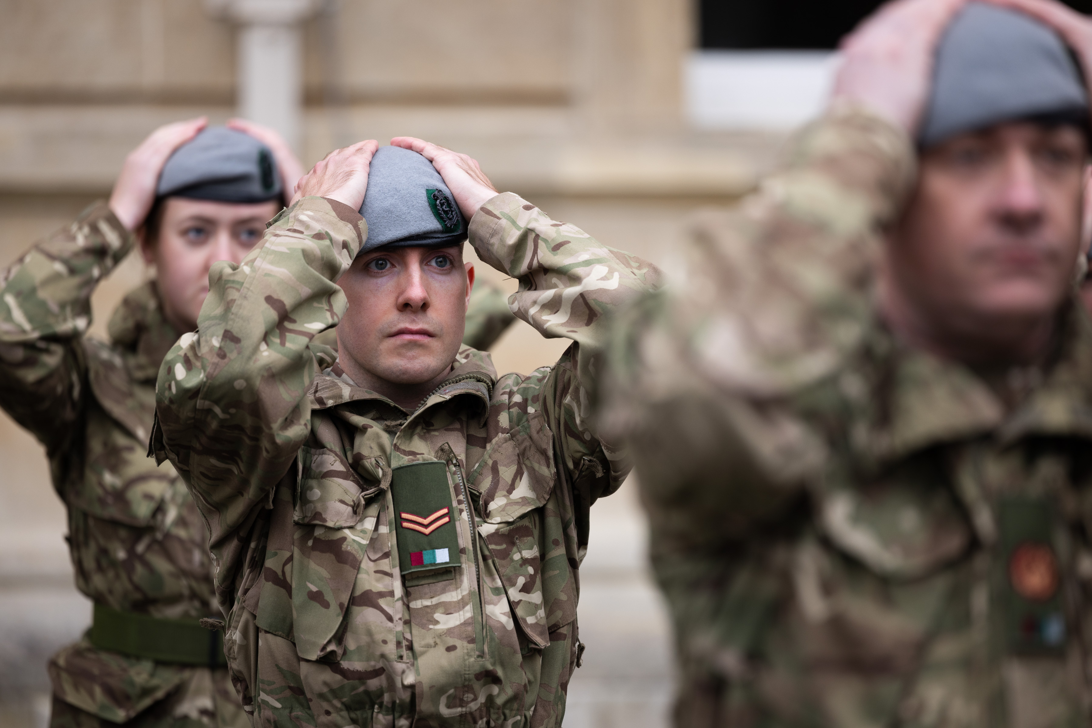 Soldiers in uniform place their new berets on their heads. 
