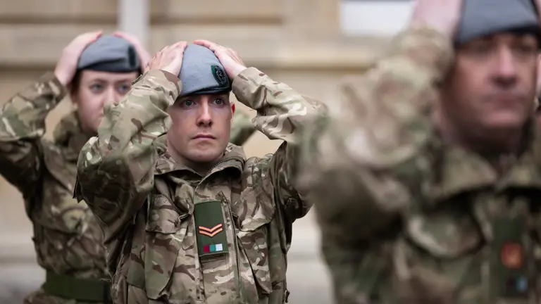 Soldiers in uniform place their new berets on their heads.