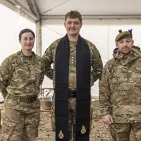 A British Army padre is pictured in between a man and a woman in uniform.